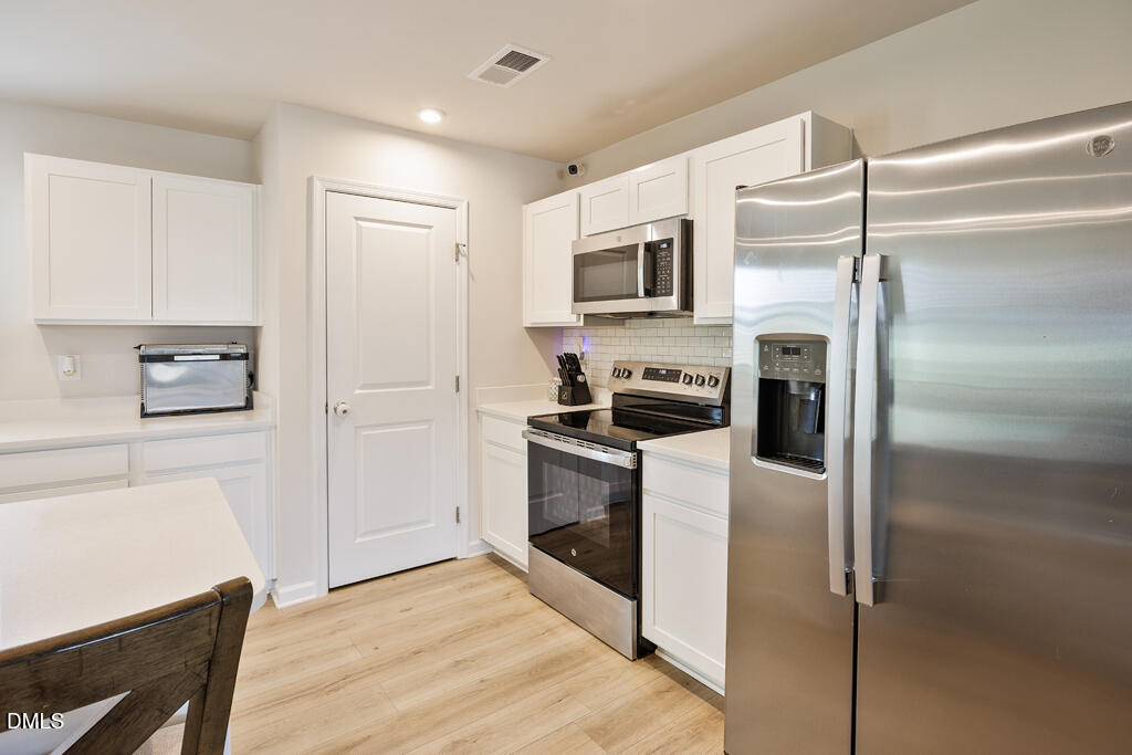 4468 Captain Falls Drive Raleigh, NC 27610 - Photo 8 of 36 a kitchen with a refrigerator stainless steel appliances wooden floor and cabinets