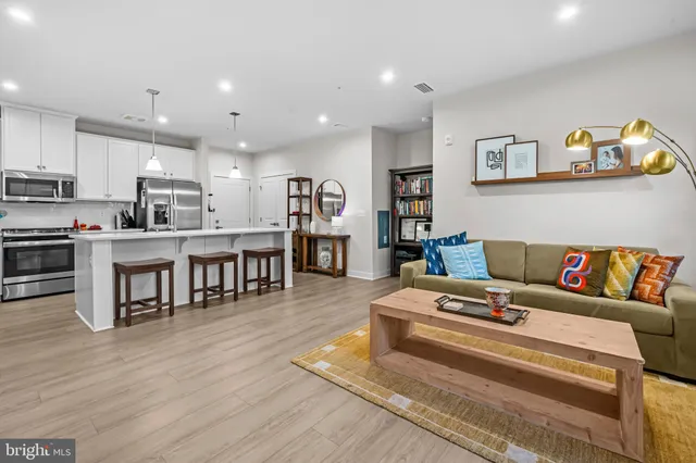 a living room with stainless steel appliances furniture and a kitchen view
