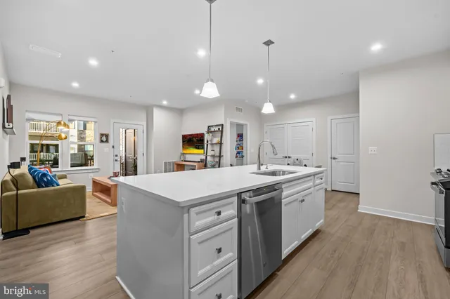 a large kitchen with kitchen island a stove a sink a refrigerator and a dining table with wooden floor