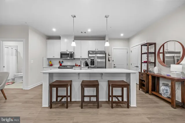 a kitchen with stainless steel appliances granite countertop a table chairs refrigerator and microwave