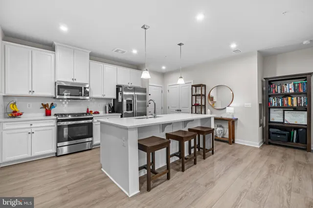 a kitchen with kitchen island granite countertop a sink cabinets and wooden floor