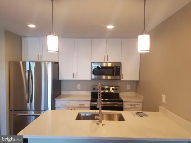 a kitchen with stainless steel appliances a stove a refrigerator a sink a counter top space and cabinets