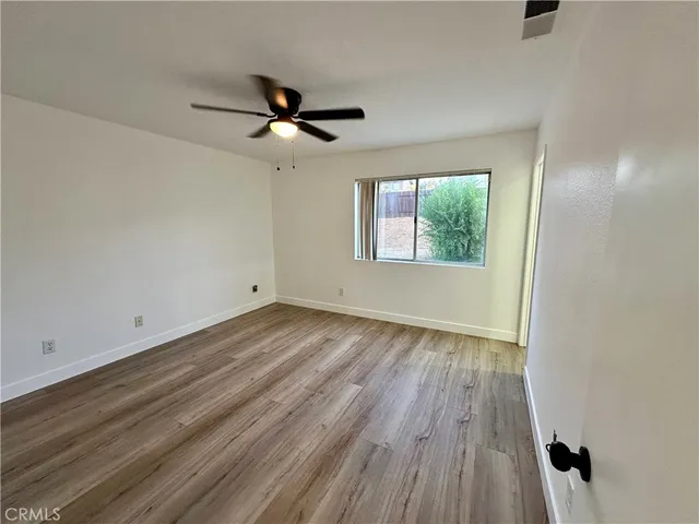 an empty room with wooden floor fan and windows