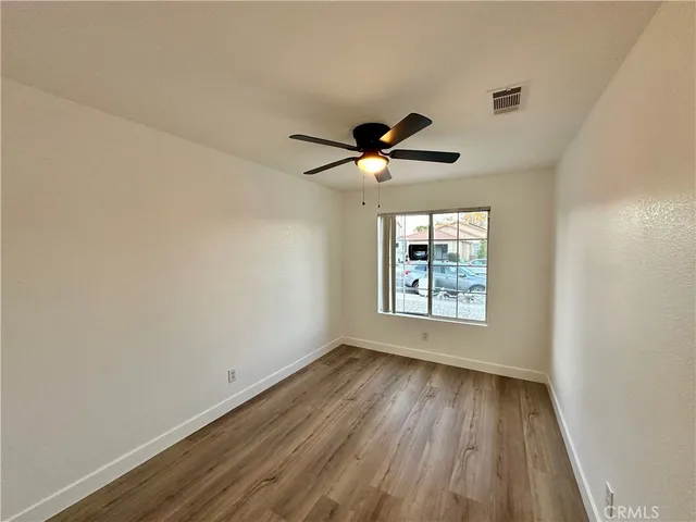 a view of an empty room with a window and wooden floor