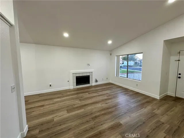 a view of empty room with wooden floor and fireplace
