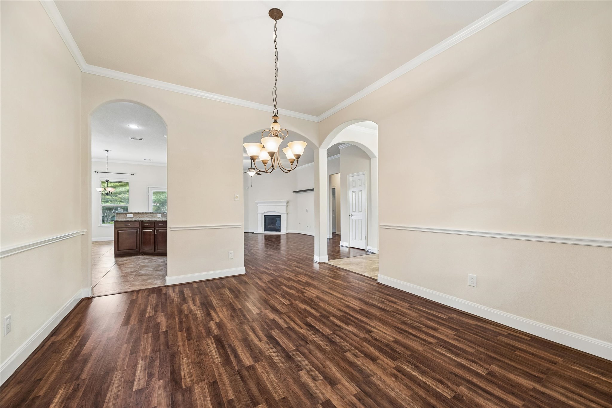 2214 Wembley Way Rosenberg, TX 77471 - Photo 10 of 35 Spacious room featuring wood-finish flooring, arched doorways, a decorative chandelier, crown molding, and wainscoting