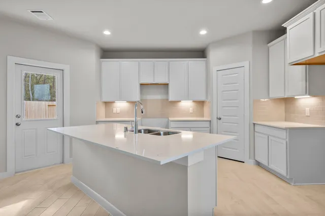 a kitchen with kitchen island a sink a stove a refrigerator and white cabinets