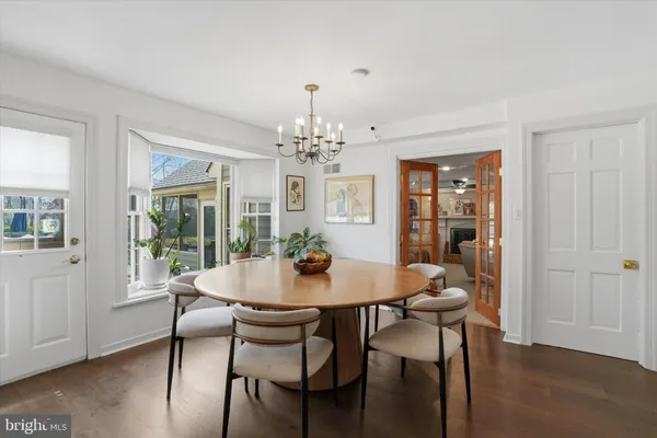 a dining room with furniture wooden floor a potted plant and a chandelier