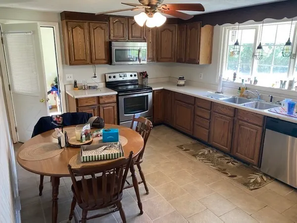 a kitchen with stainless steel appliances granite countertop a sink a stove a dining table and chairs