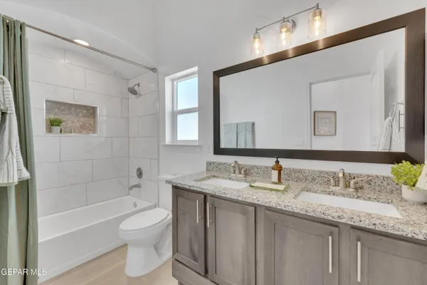a bathroom with a granite countertop sink mirror vanity bathtub and a toilet