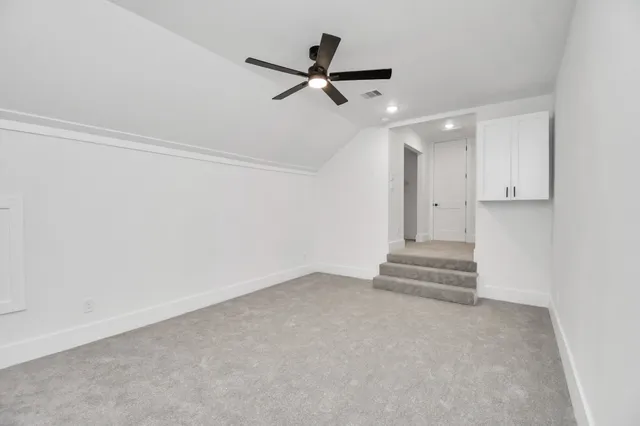 an empty room with a ceiling fan and windows