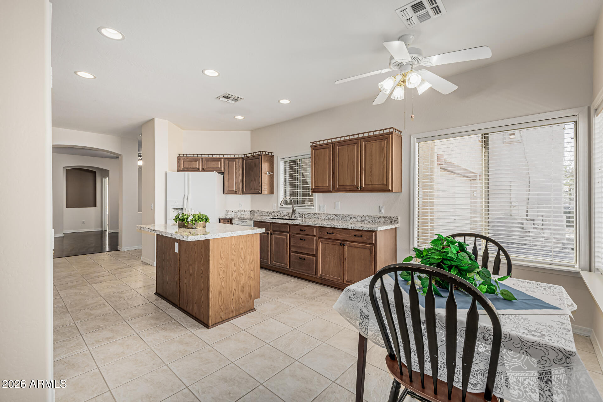 a open kitchen with stainless steel appliances granite countertop a refrigerator a sink a stove a dining table and chairs