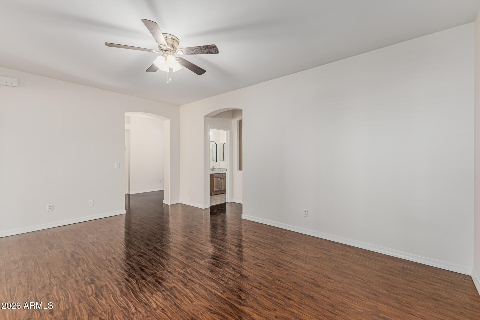 1650 South Crismon Road, Unit 16 Mesa, AZ 85209 - Photo 12 of 39 a view of an empty room with wooden floor and a ceiling fan