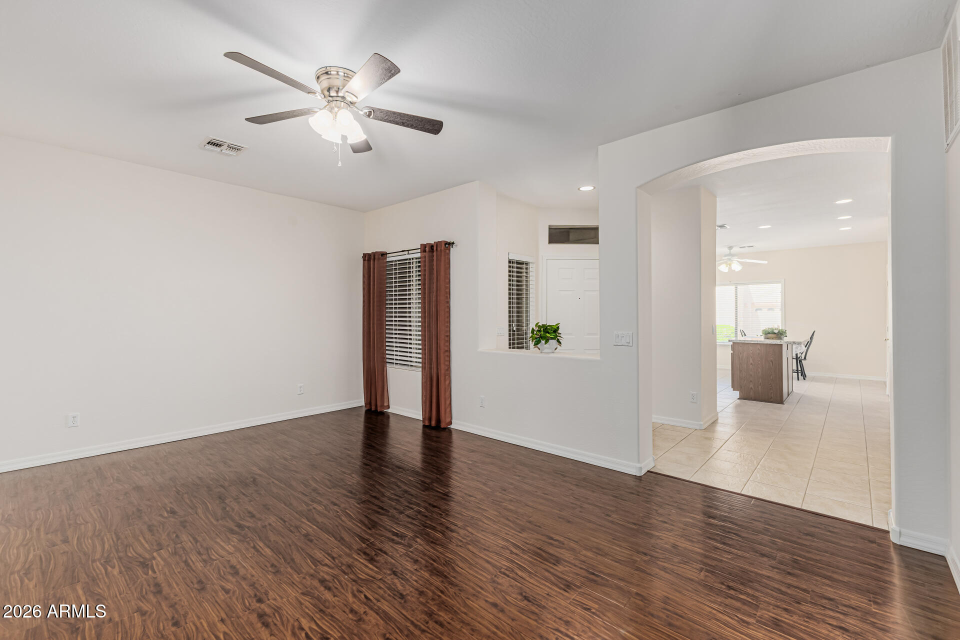 1650 South Crismon Road, Unit 16 Mesa, AZ 85209 - Photo 8 of 39 a view of an empty room with wooden floor and a ceiling fan