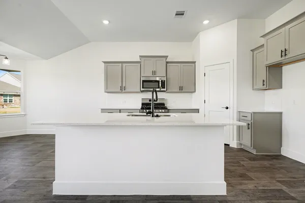 a room with stainless steel appliances granite countertop a sink dishwasher a microwave oven and white countertops with wooden floor