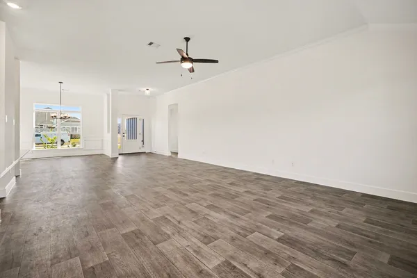 a view of an empty room with window and wooden floor