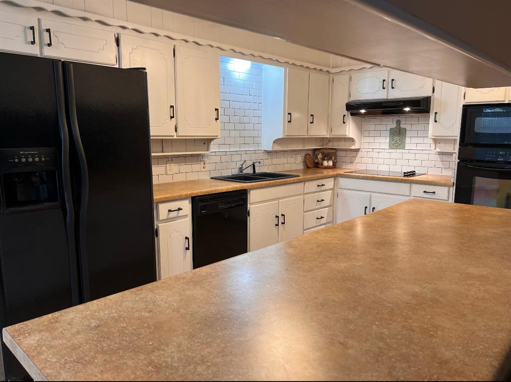 840 South Ridgeway Drive Cleburne, TX 76033 - Photo 7 of 25 Kitchen featuring black appliances, backsplash, white cabinetry, and light countertops