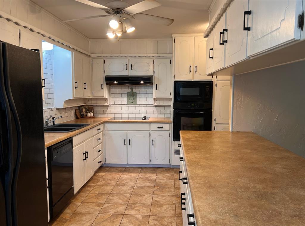 840 South Ridgeway Drive Cleburne, TX 76033 - Photo 9 of 25 Kitchen with black appliances, backsplash, light countertops, white cabinetry, and a textured wall