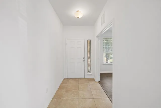 a view of a hallway with wooden floor and a bathroom