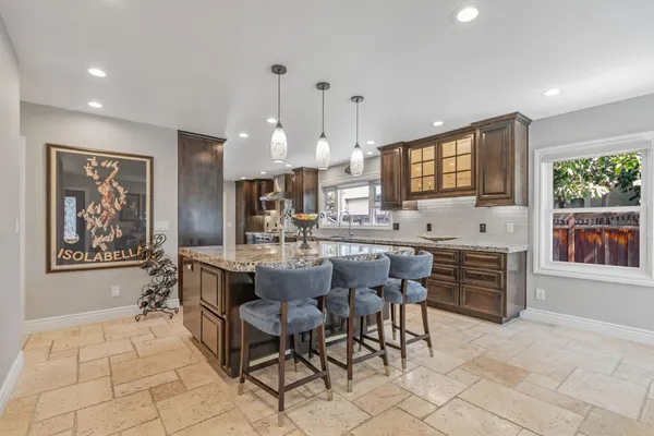 a large kitchen with kitchen island granite countertop a stove a sink a dining table and chairs