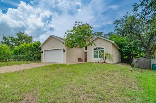 a backyard of a house with plants and large tree