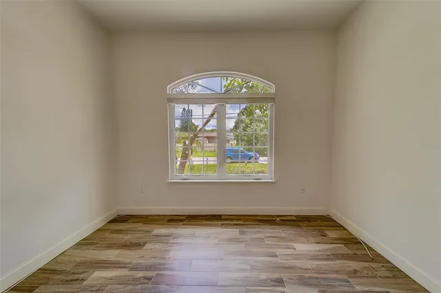 a view of an empty room with wooden floor and a window