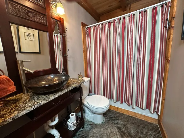 a bathroom with a granite countertop sink toilet and mirror