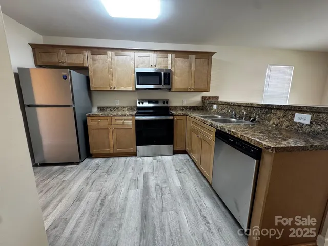 a kitchen with granite countertop a refrigerator stove top oven and sink