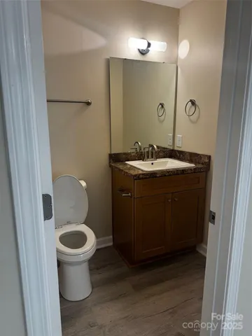 a bathroom with a granite countertop sink a toilet a mirror and vanity