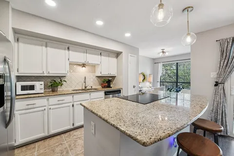 a kitchen with sink stove and white cabinets with wooden floor