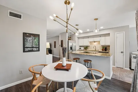 a kitchen with stainless steel appliances granite countertop a sink a stove a dining table and chairs