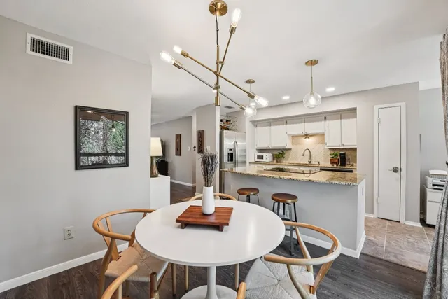 a kitchen with stainless steel appliances granite countertop a sink a stove a dining table and chairs