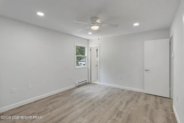 an empty room with a fan & a ceiling fan