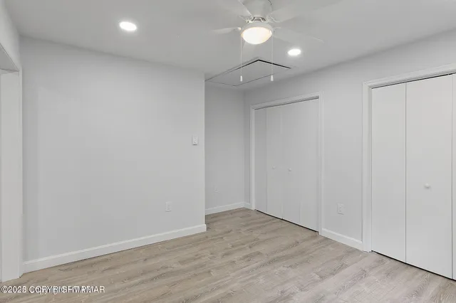 an empty room with wooden floor and fan