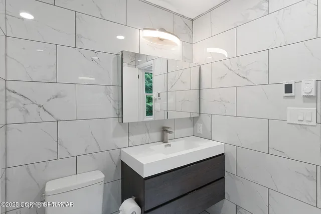 a bathroom with a sink toilet and large mirror