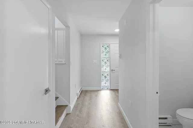 a view of a hallway with wooden floor and a bathroom
