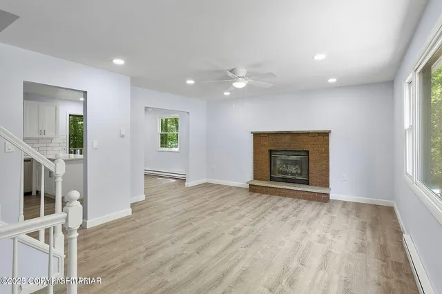 a view of an empty room with a window and fireplace