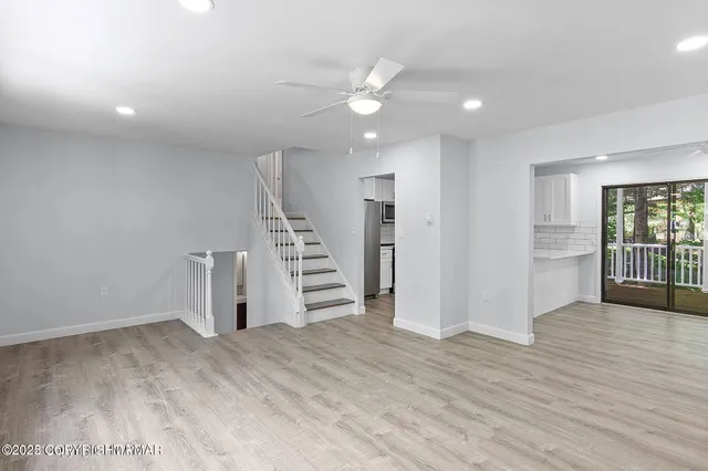 a view of empty room with wooden floor and staircase