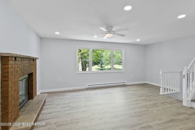 an empty room with windows fireplace and natural light