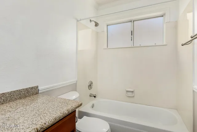 a bathroom with a granite countertop sink a toilet and a bathtub