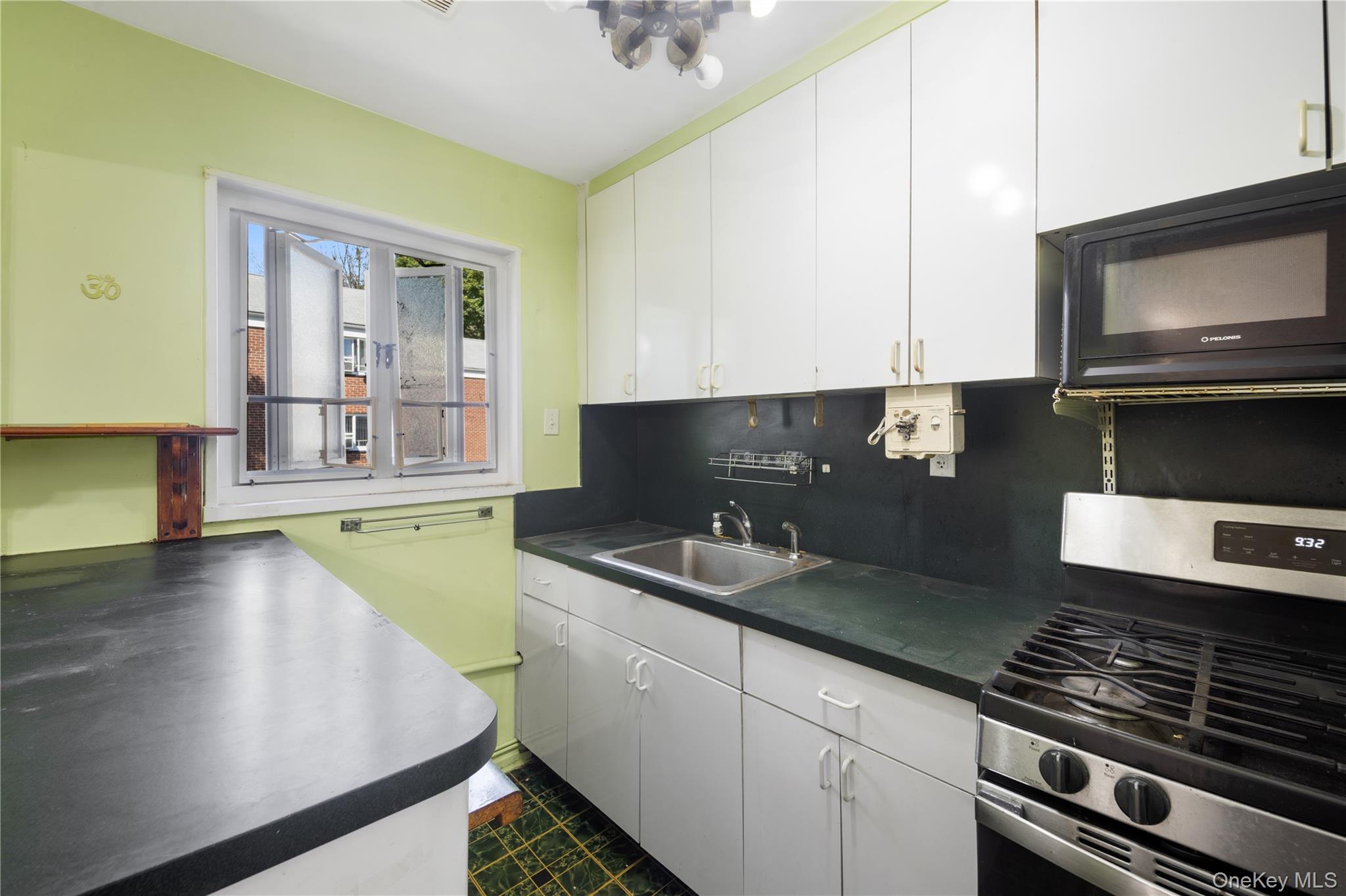 226-29 Manor Road, Unit UPPR Queens, NY 11427 - Photo 7 of 21 Kitchen with stainless steel gas range, dark countertops, white cabinets, black microwave, and decorative backsplash
