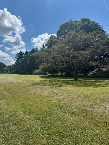 a view of a large pool with lawn chairs under an umbrella