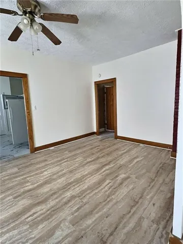 an empty room with wooden floor fan and windows