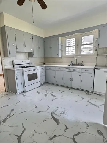a kitchen with granite countertop a stove a sink a refrigerator and white cabinets