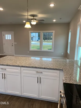 a kitchen with granite countertop a sink and white cabinets