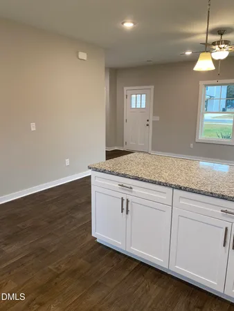 a kitchen with granite countertop white cabinets and a wooden floor