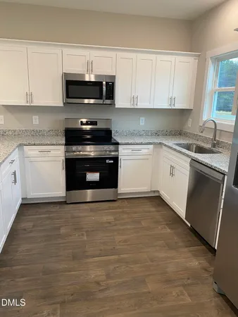a kitchen with granite countertop a stove a sink and a microwave