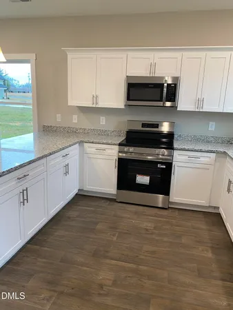 a kitchen with granite countertop a stove a microwave a sink and cabinets