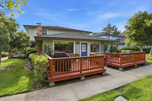 a view of a house with a wooden deck and furniture