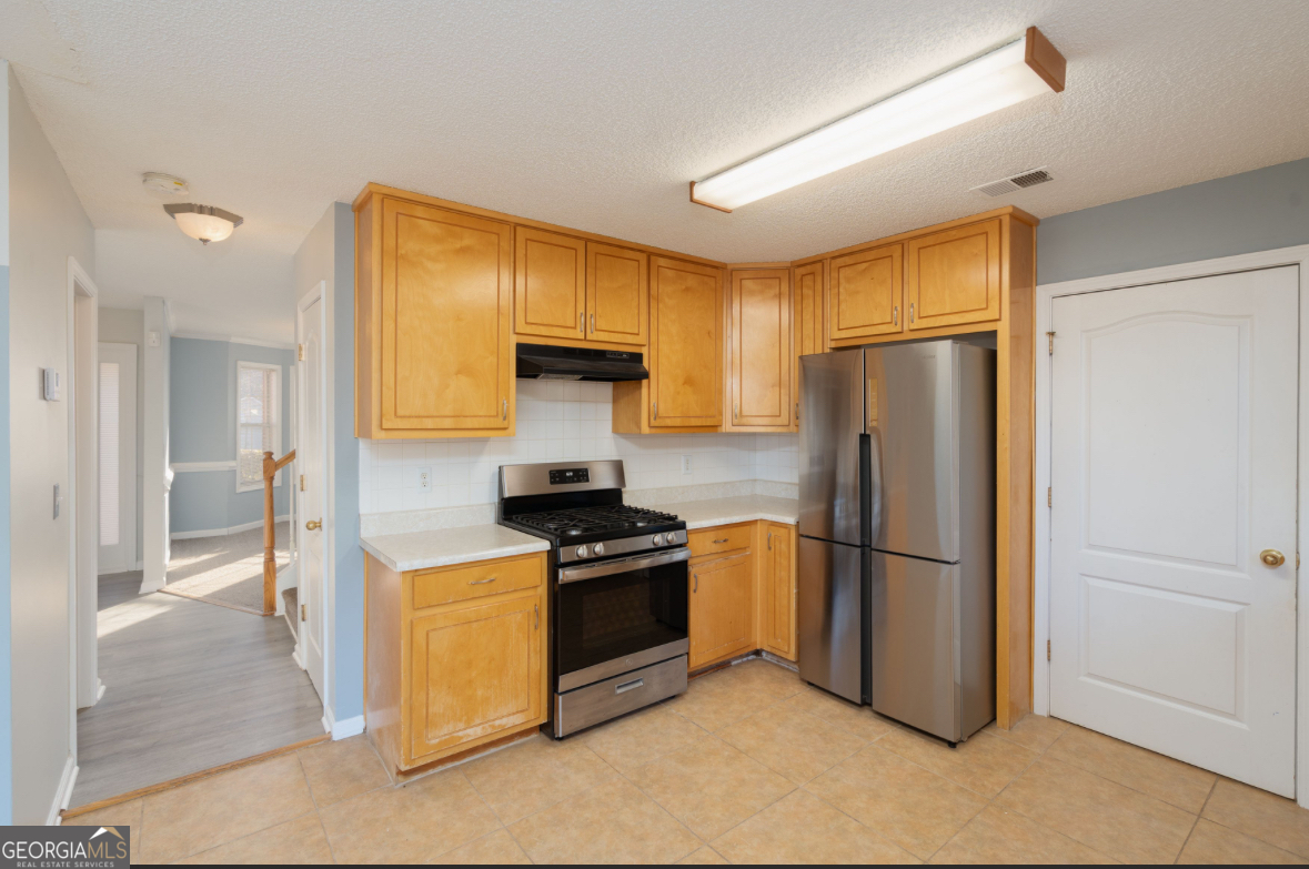 4414 Mitchells Ridge Drive Ellenwood, GA 30294 - Photo 8 of 25 a kitchen with a refrigerator a stove a washer dryer and white cabinets
